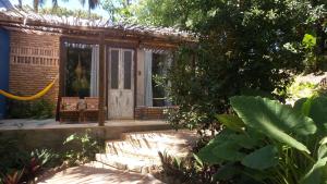 a small building with a wooden door in a garden at Zazen Pousada by Santoregano in Maceió