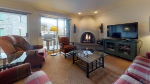a living room with a tv and a fireplace at Enzian - CoralTree Residence Collection in Vail