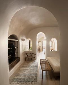 a bedroom with an archway with a bed and a table at Vora in Imerovigli