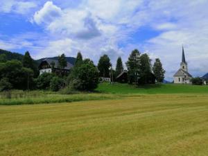 un champ avec des maisons et une église au loin dans l'établissement Ferienwohnung Bruno, à Gnesau