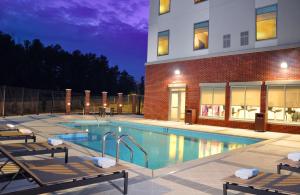 a swimming pool with two chairs next to a building at Hyatt Place Augusta in Augusta