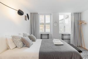ein weißes Schlafzimmer mit einem großen Bett mit zwei Handtüchern darauf in der Unterkunft Porto Center Apartments in Porto
