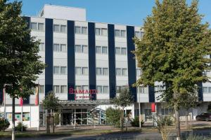 a large white building with a red sign on it at Ramada by Wyndham Hannover in Hannover