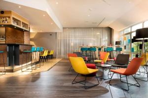 a restaurant with colorful chairs and a bar at Ramada by Wyndham Hannover in Hannover