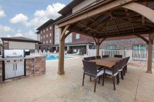 um pavilhão com uma mesa e cadeiras de madeira e uma piscina em Hawthorn Suites By Wyndham Odessa em Odessa