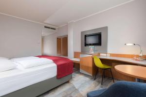 a hotel room with a bed and a desk and a table at Ramada by Wyndham Hannover in Hannover