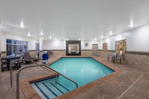 a pool in a room with a table and chairs at AmericInn by Wyndham Sioux Falls North in Sioux Falls