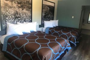 a hotel room with two beds and paintings on the wall at Super 8 by Wyndham Spring/North Houston in Spring