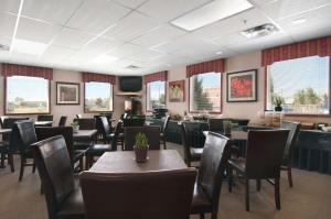 - une salle à manger avec des tables, des chaises et des fenêtres dans l'établissement Travelodge by Wyndham Stony Plain, à Stony Plain