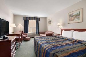 Cette chambre comprend un lit et une télévision à écran plat. dans l'établissement Travelodge by Wyndham Stony Plain, à Stony Plain