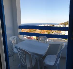 een tafel en stoelen op een balkon met uitzicht op de oceaan bij Résidence lilia jabal mdiq in M'diq