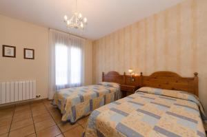 a bedroom with two beds and a chandelier at Casa Puyuelo Tierrantona in Tierrantona