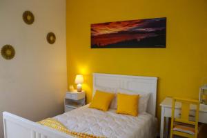 a yellow bedroom with a white bed with yellow pillows at Vista do Norte - Northern View! in Santo António