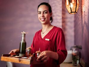 a woman holding a table with a bottle of wine at Le Médina Essaouira Thalassa Sea & Spa - MGallery Collection in Essaouira +37 photos
