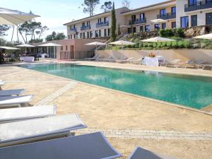 ein Pool in einem Hotel mit Stühlen und Sonnenschirmen in der Unterkunft Mercure Brignoles Golf de Barbaroux & Spa in Brignoles