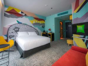ibis Styles Tbilisi Center في تبليسي: غرفة نوم مع سرير وجدار ملون