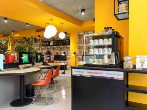 una tienda con paredes amarillas, mesas y sillas naranjas en ibis Styles Tbilisi Center, en Tiflis