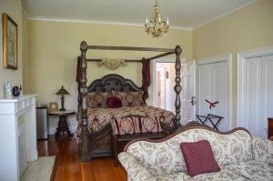 a bedroom with a bed and a couch and a chandelier at 1912 Bed and Breakfast in Sumter