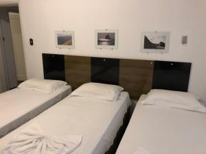 2 Einzelbetten in einem Zimmer mit 3 Bildern an der Wand in der Unterkunft AP na Rua das Flores in Curitiba