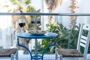 una tavola con un piatto di cibo e un bicchiere di vino di Alesahne Beach Hotel a Kamari