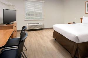 a bedroom with a bed and a desk with a television at Woodspring Suites Huntsville/ Madison in Madison