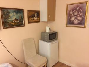 a room with a microwave and a chair and paintings at Central Greenwich guest rooms in London