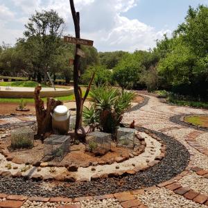 a garden with a sign and some plants on a path at Die Plasie on-suite rooms in Hartbeespoort