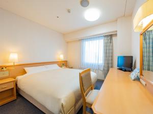 una camera d'albergo con un grande letto e una TV di Hotel Grand Terrace Obihiro a Obihiro