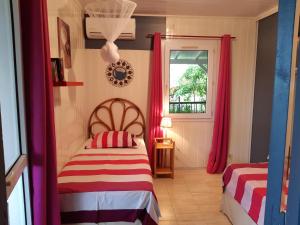 a bedroom with two beds and a window with red curtains at Les Gites Capra - Papaye in Bouillante