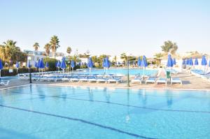 a large swimming pool with blue umbrellas and chairs at Mastichari Bay Hotel in Mastihari