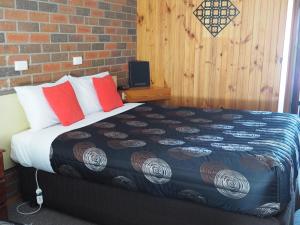 a bed in a room with a brick wall at Country Road Motel St Arnaud in Saint Arnaud