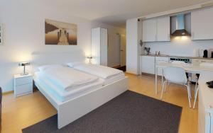 ein weißes Schlafzimmer mit einem weißen Bett und einer Küche in der Unterkunft Lac 16 in St. Moritz