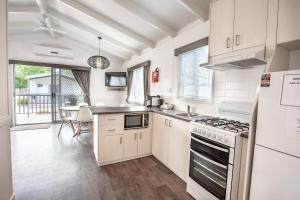 a kitchen with white cabinets and a stove top oven at Geelong Holiday Park in Geelong
