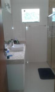 a white bathroom with a sink and a shower at Conforto e Comodidade Porto Seguro BA in Porto Seguro