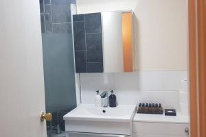 a bathroom with a white sink and a mirror at Garland Modern House With Parking & Garden Croydon in Croydon