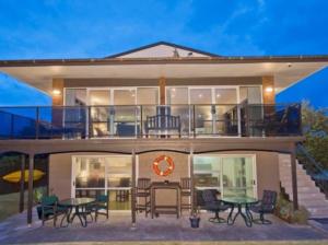 una casa con terraza con mesas y sillas en Waetford Road Lodge, en Matapouri