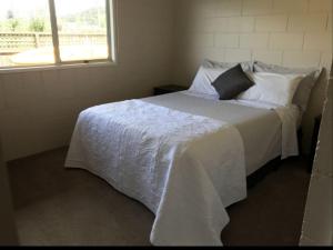 een slaapkamer met een wit bed en een raam bij Waetford Road Lodge in Matapouri
