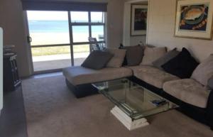 un soggiorno con divano e tavolo in vetro di Waetford Road Lodge a Matapouri