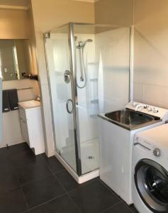 a bathroom with a shower and a washing machine at Waetford Road Lodge in Matapouri