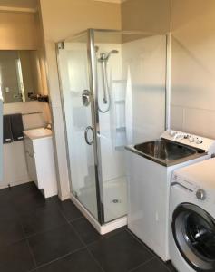 y baño con ducha y lavadora. en Waetford Road Lodge, en Matapouri