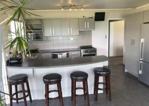 a kitchen with a counter with four bar stools at Waetford Road Lodge in Matapouri