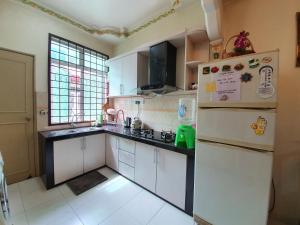 een keuken met witte kasten en een koelkast bij Cempaka Residence Homestay in Melaka