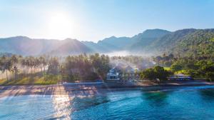 a house on the shore of a river with mountains at Living Asia Resort and Spa in Senggigi