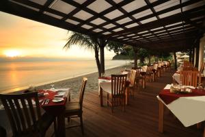 a restaurant with tables and chairs on the beach at Living Asia Resort and Spa in Senggigi
