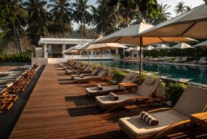 a row of lounge chairs and umbrellas next to a swimming pool at Living Asia Resort and Spa in Senggigi