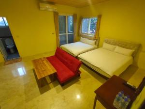 een kleine kamer met 2 bedden en een rode stoel bij 7街160民宿 in Jian