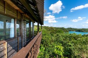 a house with a balcony with a view of a lake at Tree-house Hotel Morinosubako in Nakijin