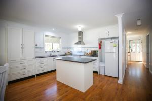 uma cozinha com armários brancos e um frigorífico branco em Dell-Lee Cottage em Broke