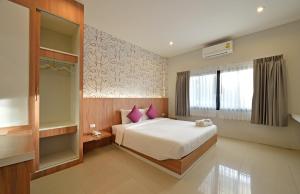 a bedroom with a bed with purple pillows and a window at Tairada Boutique Hotel in Krabi