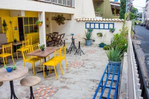 a patio with yellow chairs and tables and a building at Flor de Lis Hostel in Viçosa